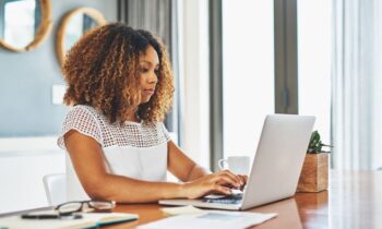 A woman searching for jobs on a laptop in her home office for blog post sign up for new job alerts