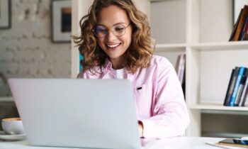 Woman working in her home office, sitting at a desk, using a laptop.