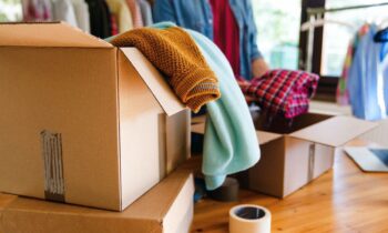 A woman sorting and packing used clothes into boxes to sell online.