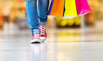 A closeup of a woman holding shopping bags while walking in the mall.