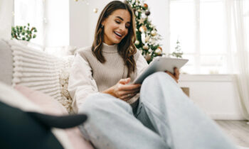 A middle aged woman sitting on the sofa looking at her iPad reading an article on ways to make Christmas cash