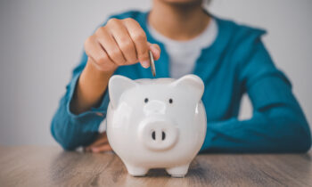 A woman putting a coin into a piggy bank for the blog post how to earn $100 a day