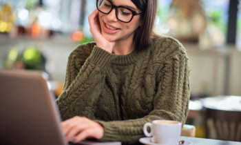A woman wearing glasses looking online for paid focus groups