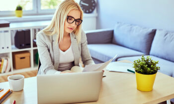 A woman with long hair and glasses reading an article on real work from home jobs