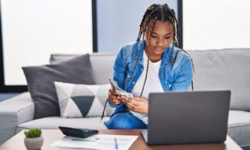 A young woman counting money and looking at her laptop for ways to make money in one hour
