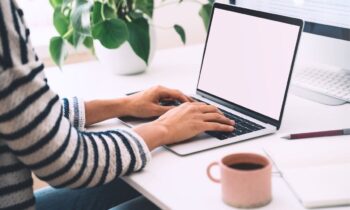 A remote worker, sitting at a desk and using a laptop to apply for jobs on the hidden job market.