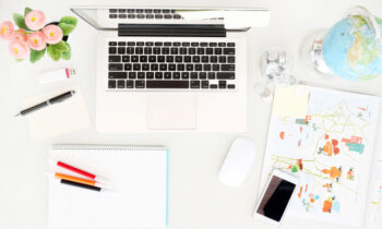 Overview of a desk space with laptop and globe for worldwide work from home jobs