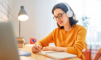 Woman working at home and writing in a notebook at a desk for blog post no interview jobs