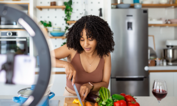 Food blogger wearing apron chopping veggies making new recipe to sell online