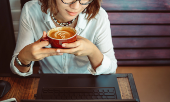 Woman at a coffee shop reading a TELUS Digital review on her laptop