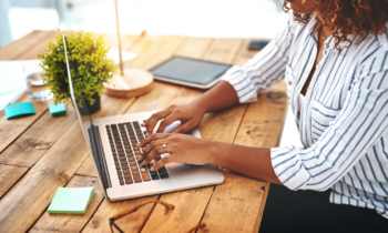 Woman sitting outside looking for a work from home marketing jobs on her laptop
