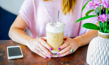 Young woman with painted finger nails drinking an iced coffee in a coffee shop for blog post free starbucks gift cards